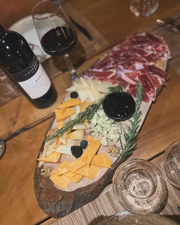 Cheese and ham board on table with wine bottle and glasses