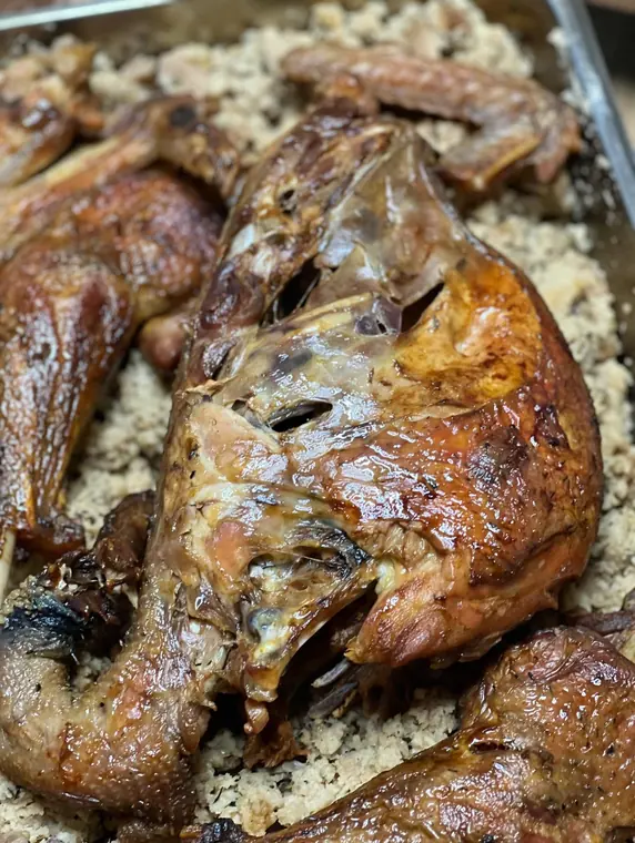 Close-up of roast poultry carcass on bulgur in tray
