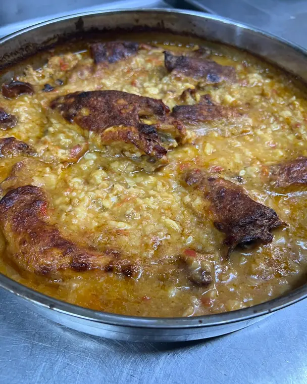 Close view of baked rice and roast meat in a metal tray