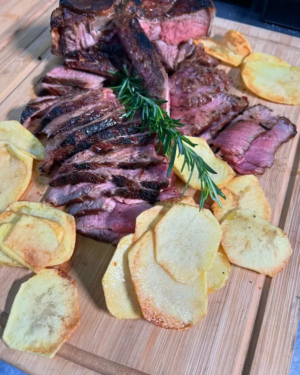 Close view of charred sliced steak with potato slices