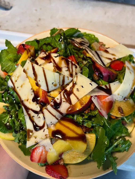Close view of salad with cheese sheets, peach and strawberry