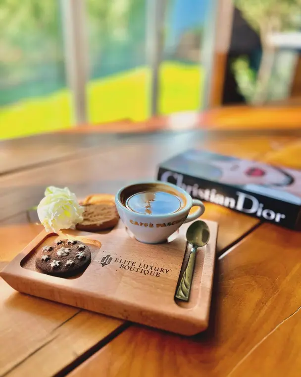 Coffee cup, biscuits and spoon on a wooden board