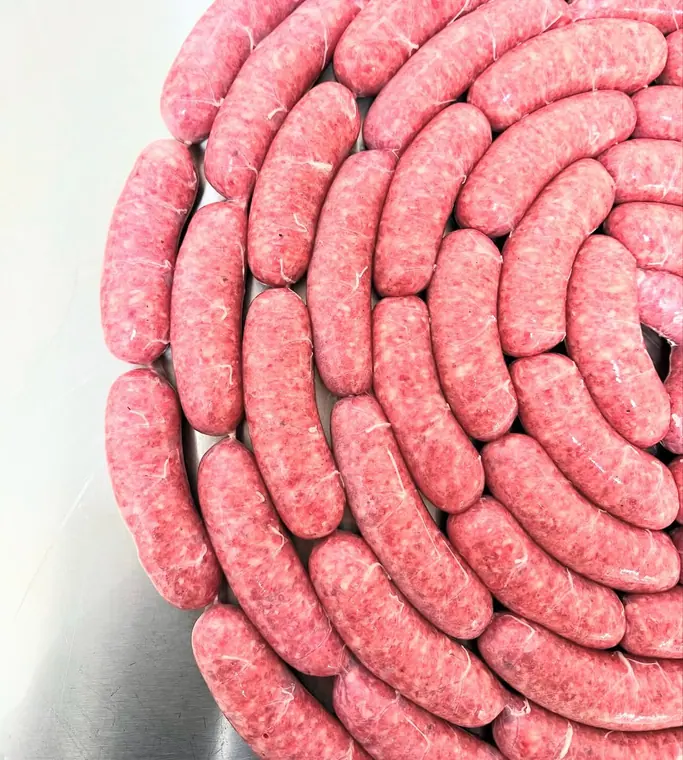 Coiled raw sausages arranged on steel tray