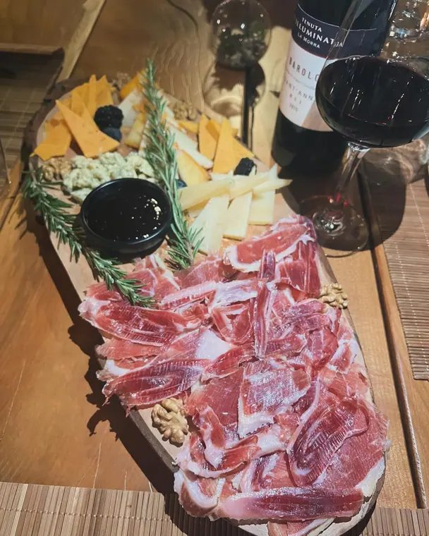 Cured ham and cheese board with red wine bottle and glass