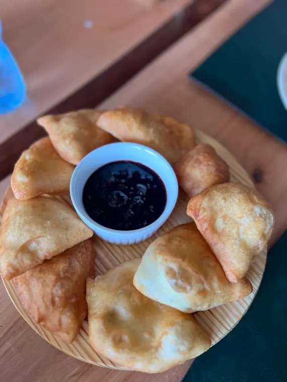 Fried dough pastries encircling white ramekin of dark jam
