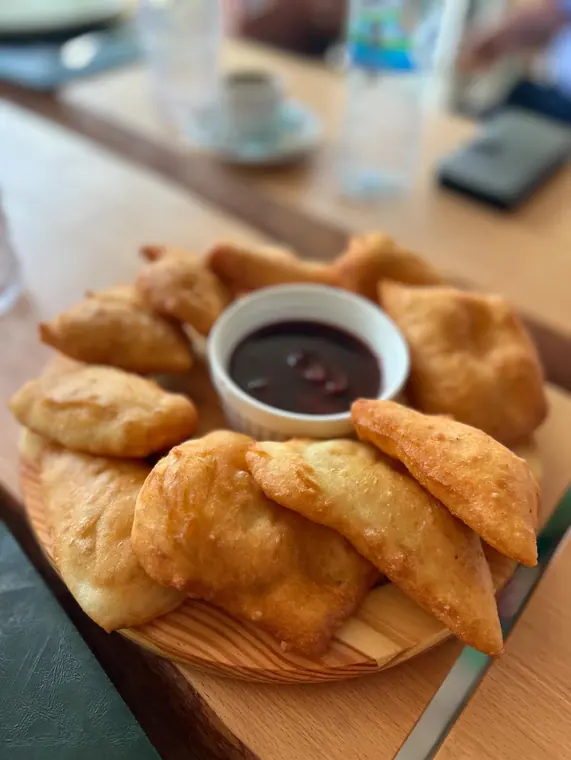 Fried dough pastries with berry dip on wooden serving board