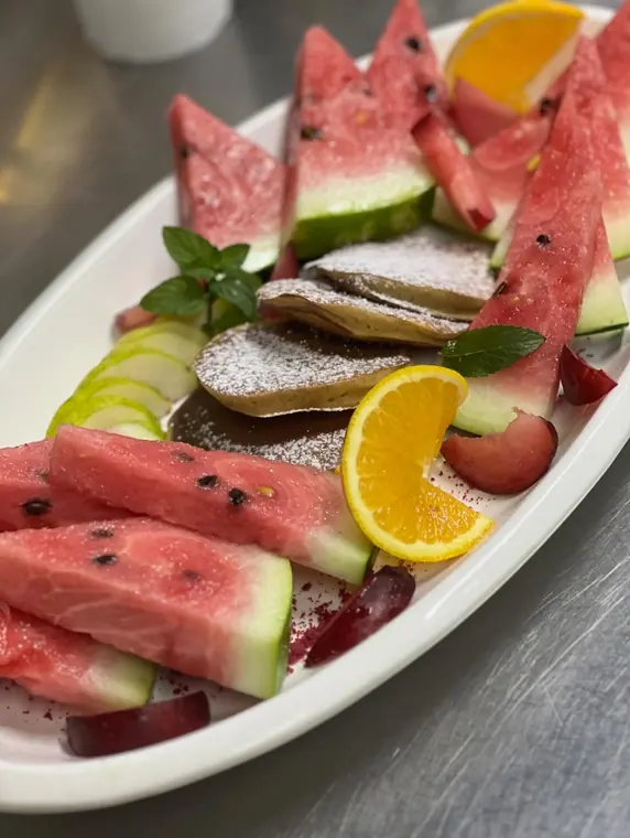 Fruit and pancake platter dusted with icing sugar
