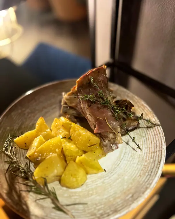 Grilled lamb ribs with roast potato wedges and rosemary on ceramic plate