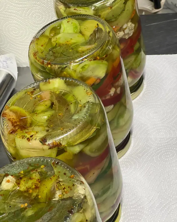 Inverted jars of pickled vegetables with bay leaf and chilli flakes