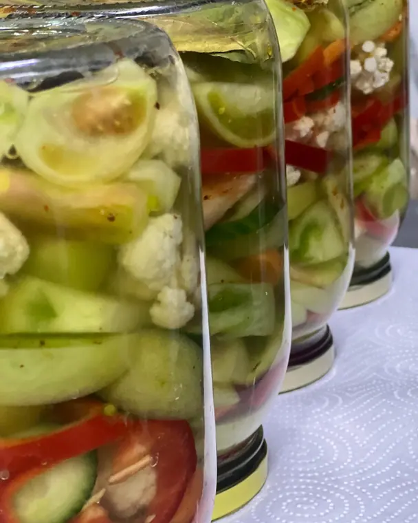 Jars of pickled tomatoes, cucumber, cauliflower and peppers