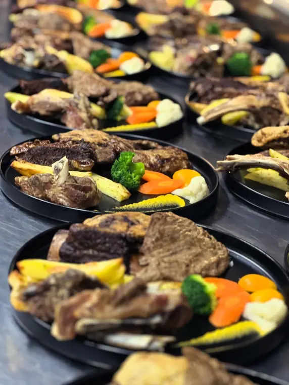 Line of plated meat courses on kitchen counter