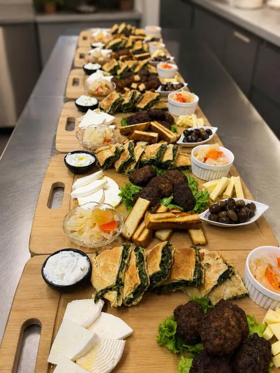 Long counter lined with appetiser boards of cheese, pastry and olives