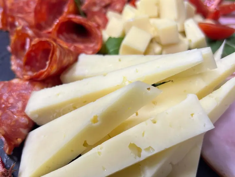 Macro of sliced cheese wedges with salami behind