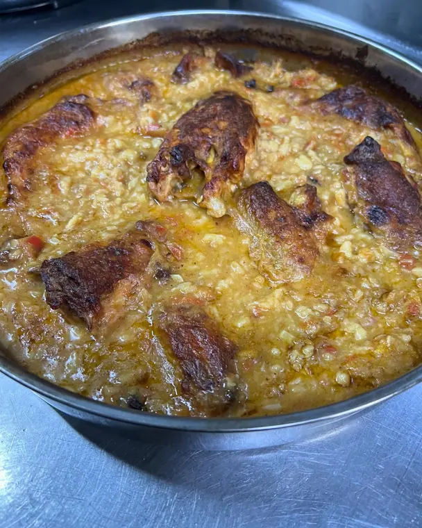 Metal tray of baked rice topped with browned meat pieces