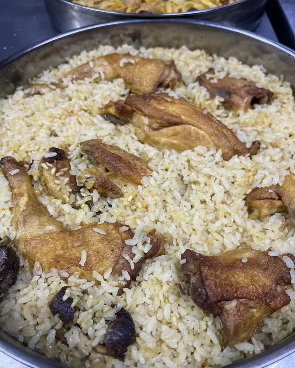 Metal tray of baked rice with roasted chicken pieces