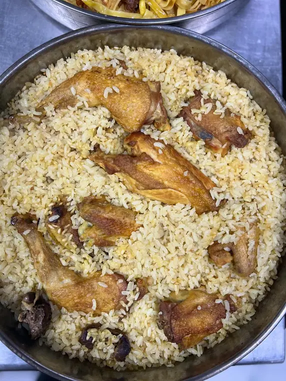 Metal tray of baked rice with roasted chicken pieces
