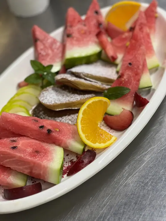 Oval plate of watermelon, pancakes, orange and plum