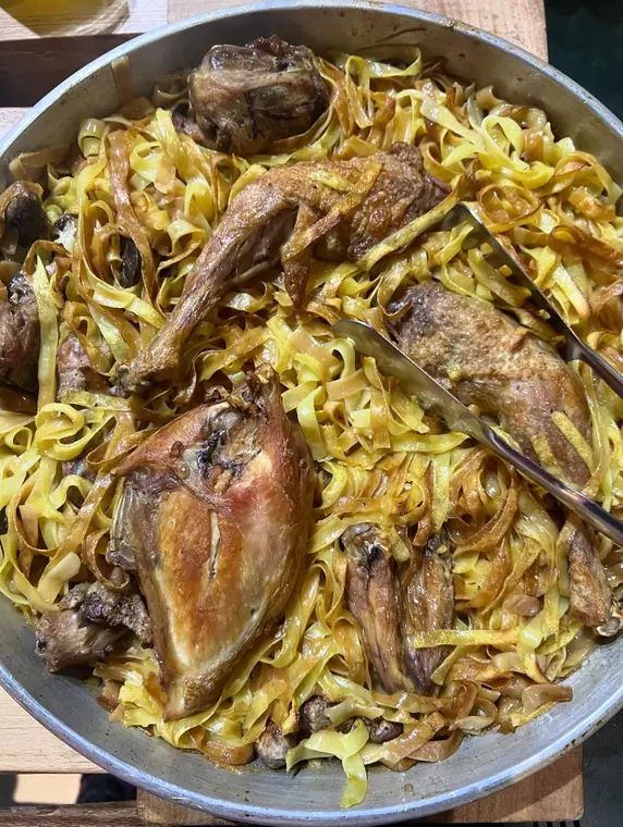 Overhead pan of ribbon pasta with roasted poultry pieces