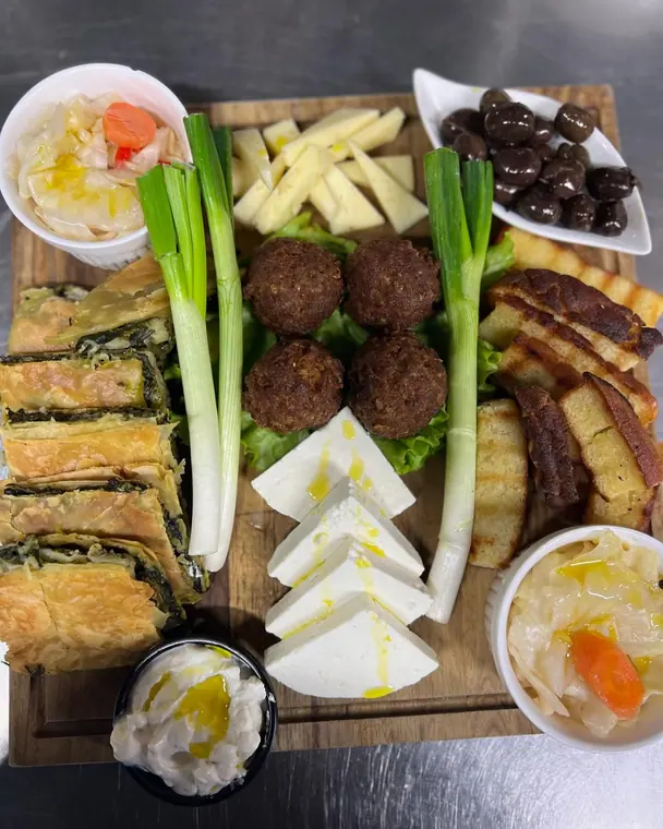Overhead starter board with spinach pie, feta, olives and dips