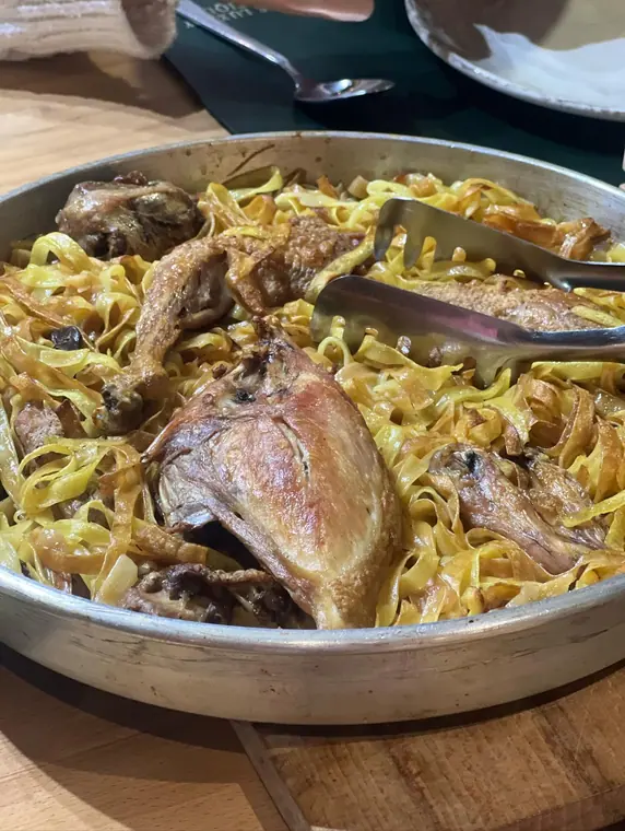 Pan of ribbon pasta with roasted poultry on wooden table