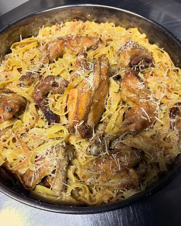 Pan of tagliatelle with chicken pieces and grated cheese