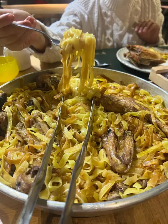 Pan of tagliatelle with poultry, fork lifting a portion