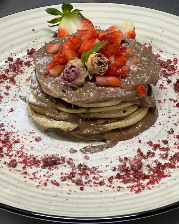 Pancake stack with chocolate spread, strawberries and berry crumb