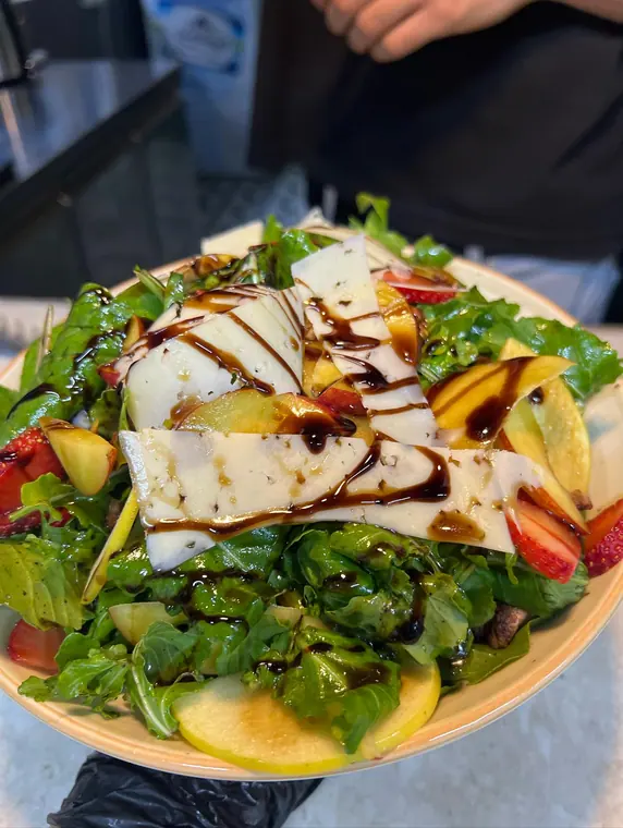 Plate of rocket salad with cheese slices, peach and balsamic