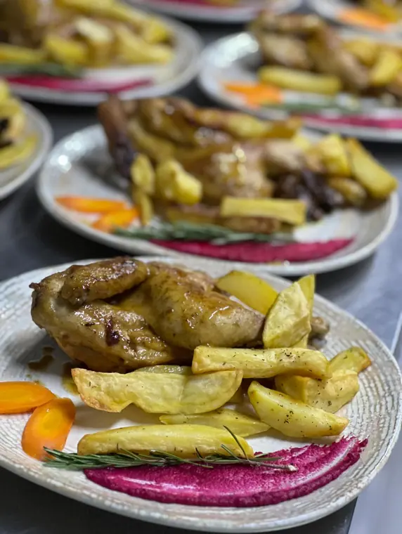 Plated roast chicken and potatoes, row of plates behind