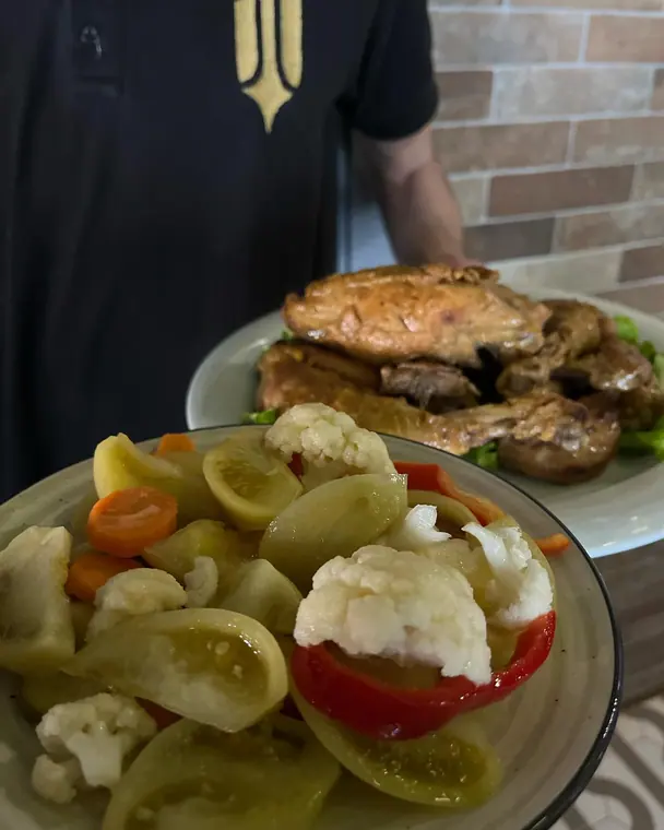 Plates of roast meat and pickled vegetables held by staff member
