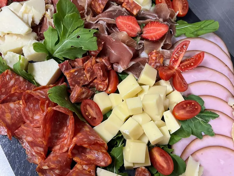 Platter of salami, prosciutto, ham, cheese cubes and tomatoes