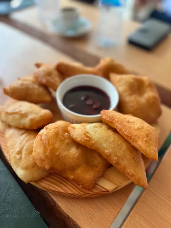 Ring of fried dough pastries with dark fruit dip on board