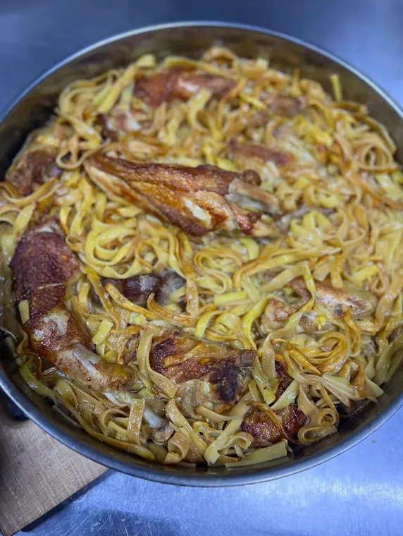 Roast chicken pieces with flat egg noodles in a metal pan