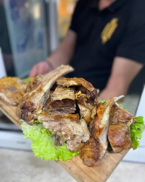 Roast lamb pieces on a wooden board held over lettuce leaves