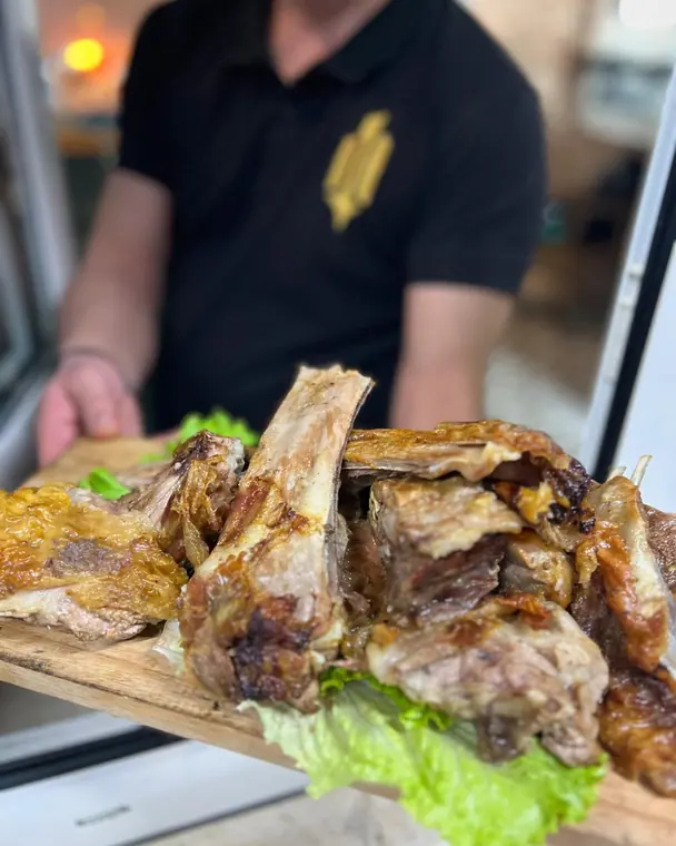Roast lamb ribs on wooden board carried by staff