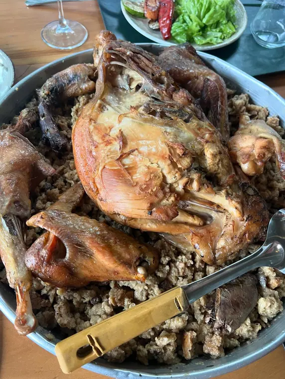 Roast poultry on bulgur in metal tray with salad plate behind