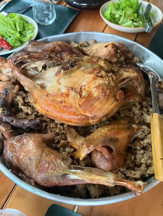 Roast poultry on bulgur with two salad bowls on wooden table