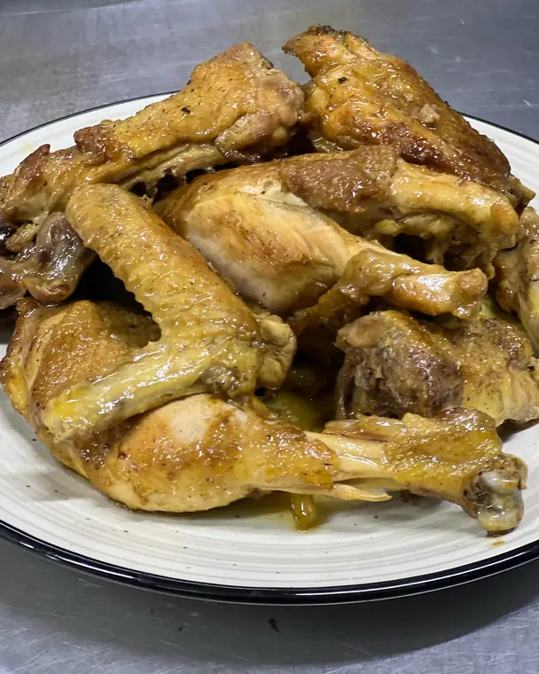 Roasted chicken pieces on white plate with black rim