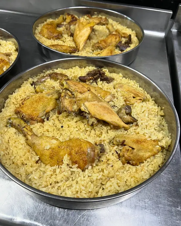 Round metal trays of rice with roasted chicken pieces