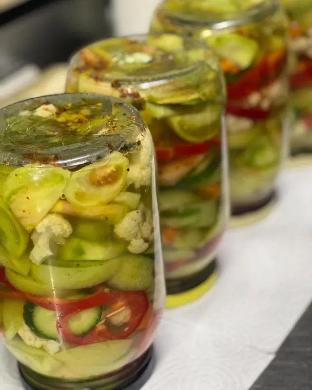 Row of jars of mixed pickled vegetables in brine