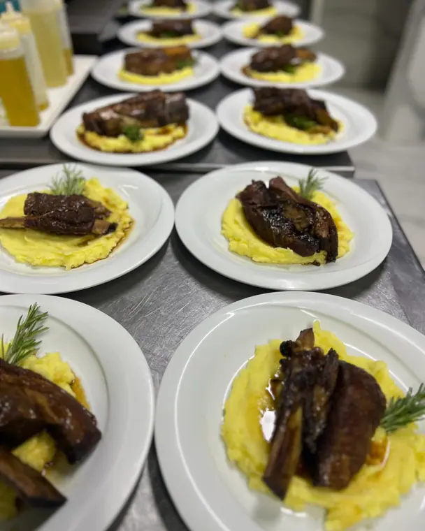 Rows of short rib and mash plates on a kitchen counter