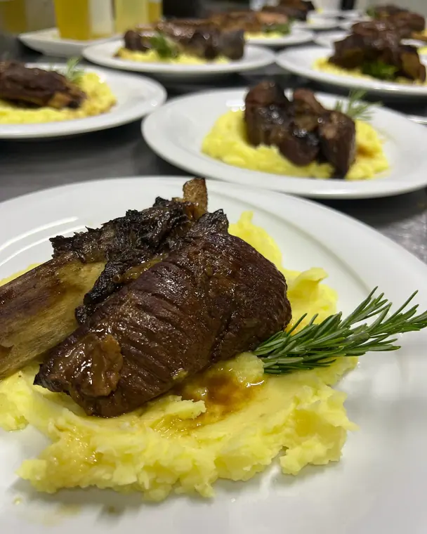 Short rib plates lined up on a stainless kitchen counter