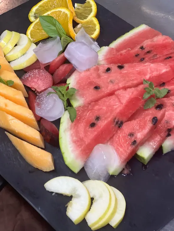 Slate board with watermelon, melon, citrus slices and ice