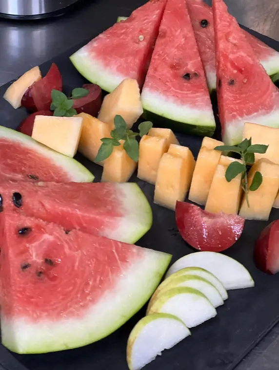 Slate board with watermelon wedges, melon cubes and apple