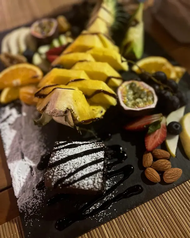 Sliced pineapple, passion fruit, grapes and brownie on slate board