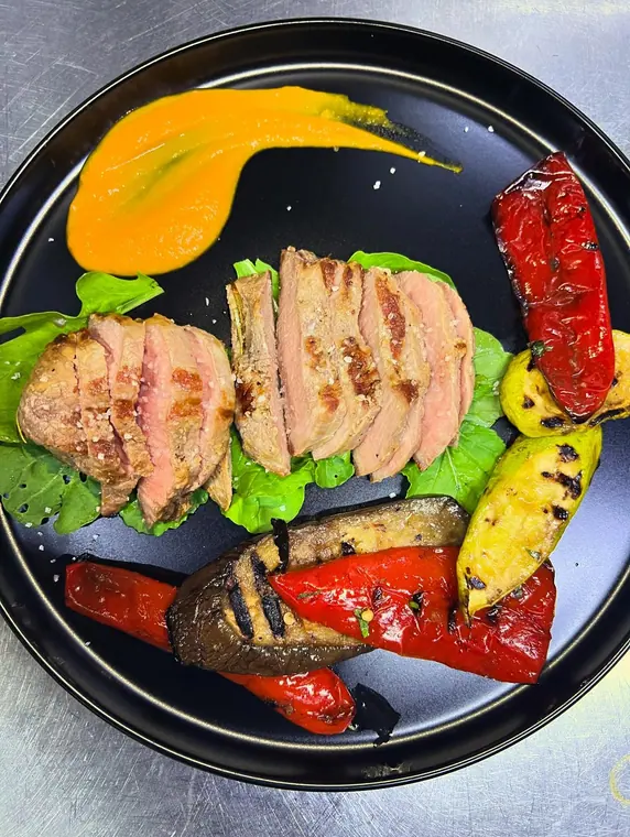 Sliced steak on greens with grilled peppers and courgette