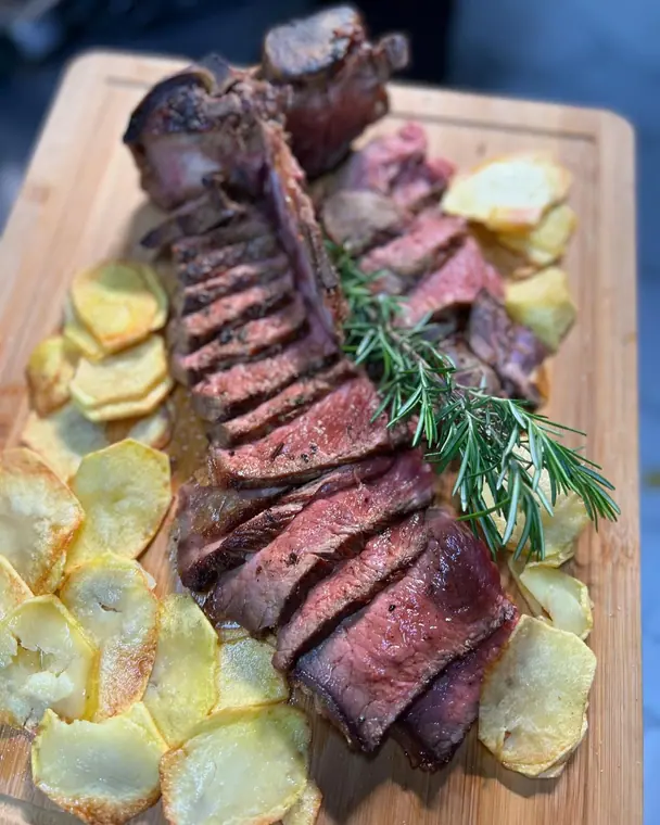 Sliced steak with rosemary sprig and fried potato slices