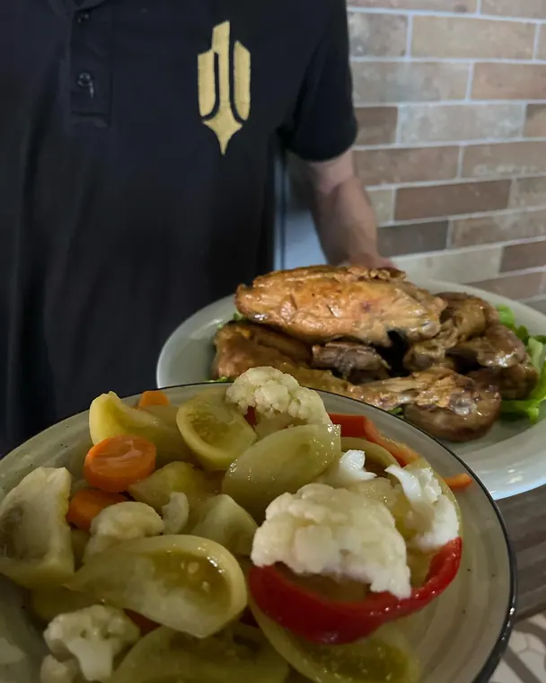 Staff member carrying plates of roast meat and pickled vegetables