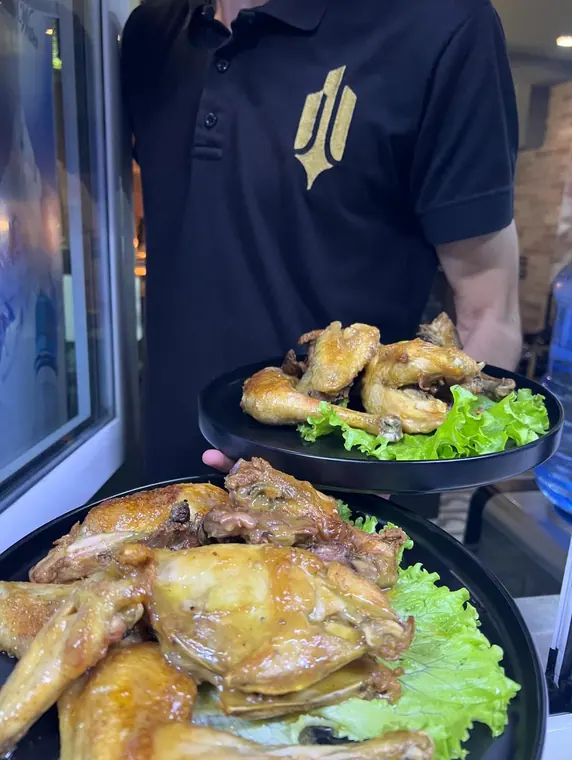 Staff member carrying two plates of roast chicken