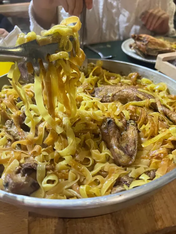 Tagliatelle with chicken served from a metal tray with tongs